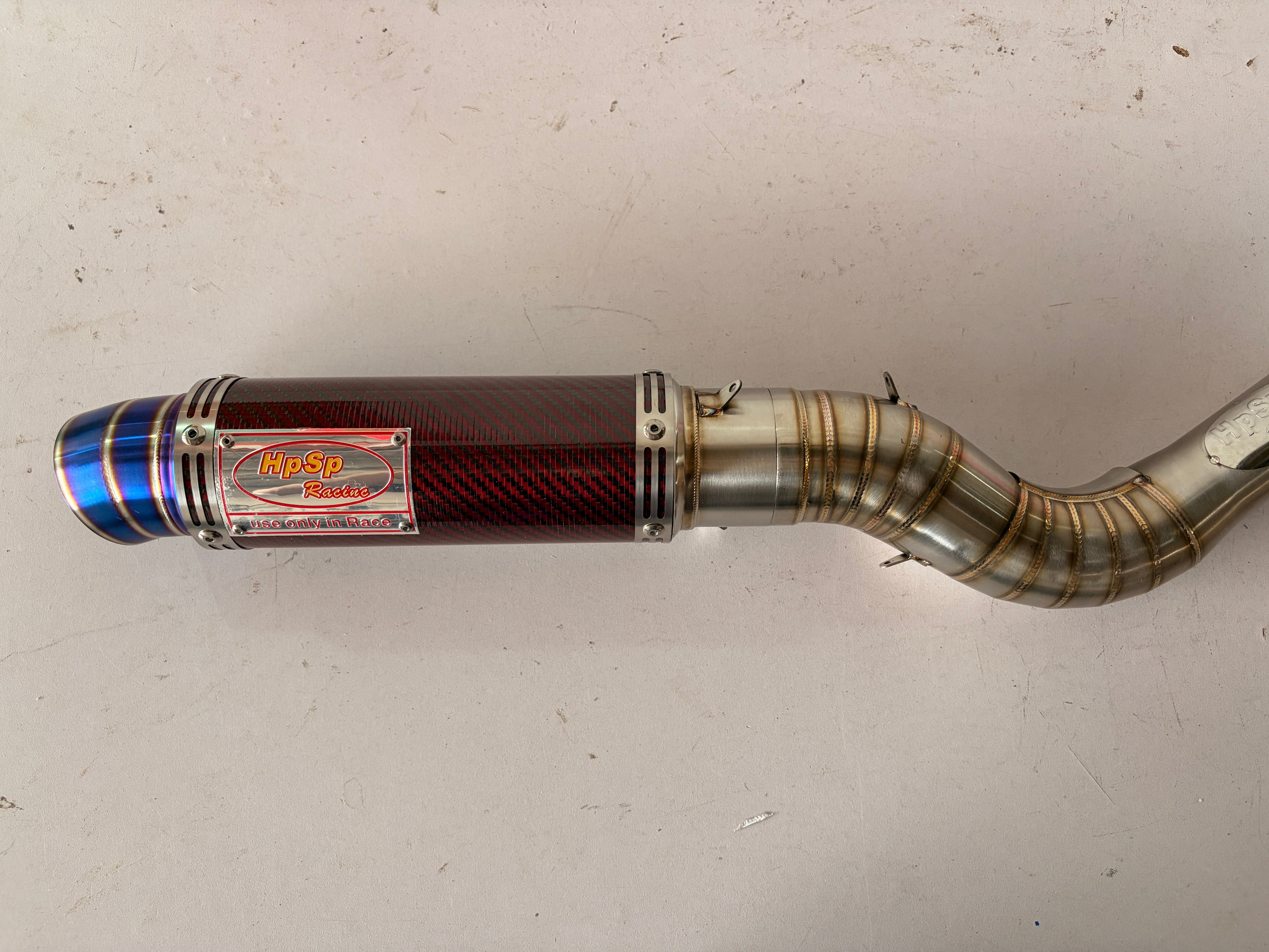 Motorcycle exhaust pipe with brand logo on a light gray background